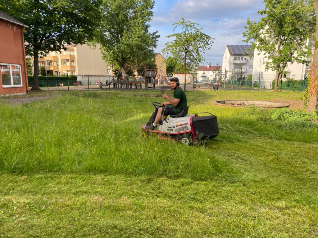 Gärtner sitzt auf Sitzrasenmäher und mäht Rasen